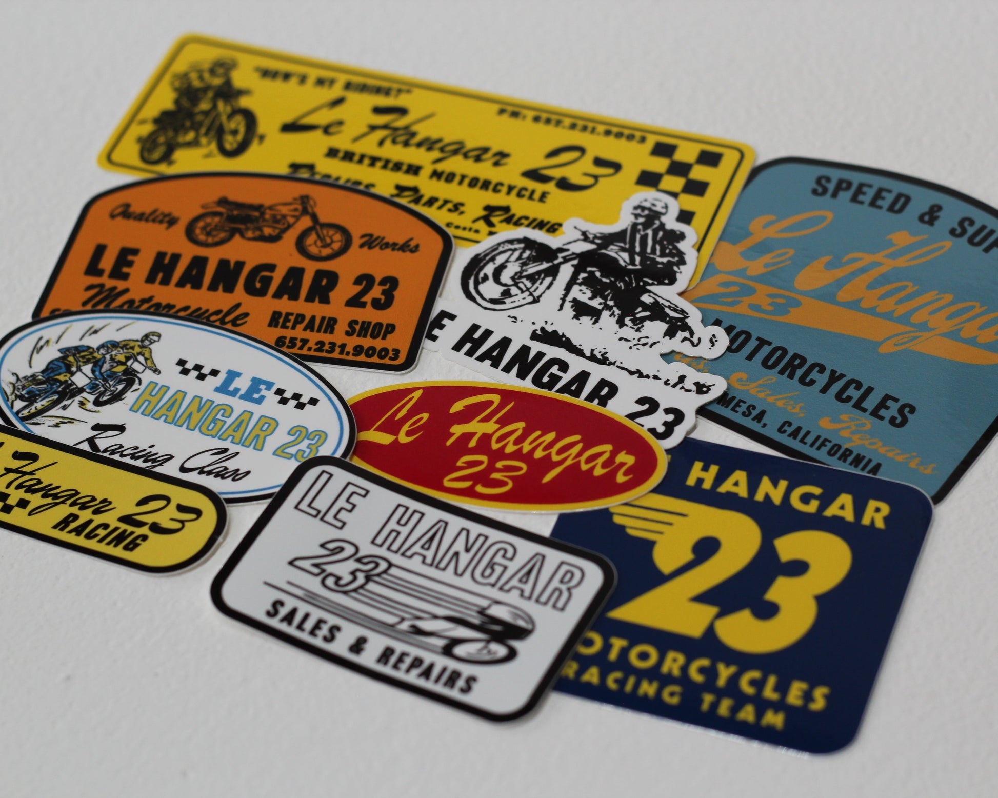 Collection of 'Le Hangar 23' motorcycle-themed stickers on a gray background